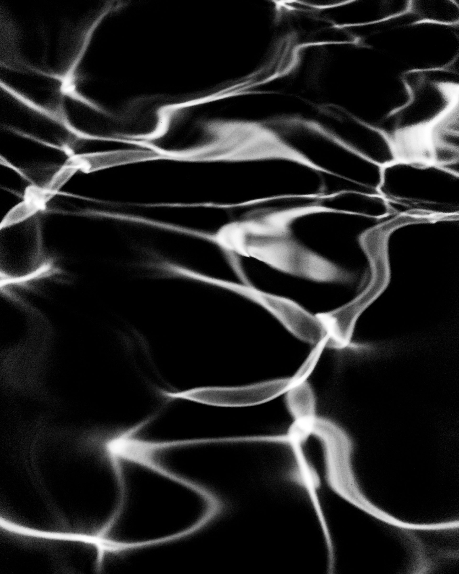 Abstract water caustics with luminous network of light on dark water — Palm Desert, California