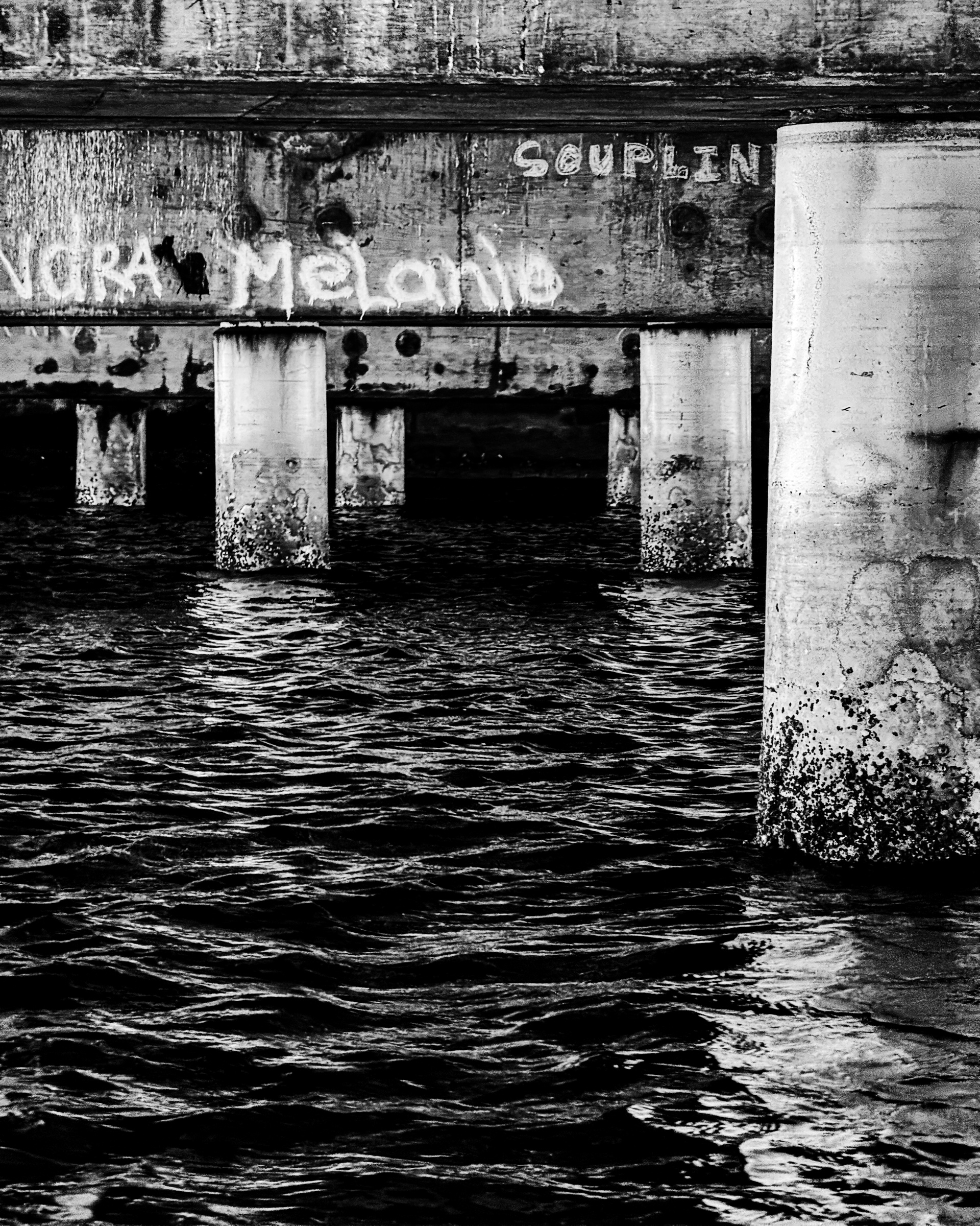 Looking up at the underside of a pier structure from the water — Long Beach, California